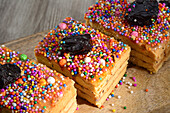 From above of sweet Turron de Dona Pepa cakes with nougat decorated with colorful dragee and prunes served on wooden table