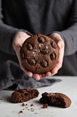 Unrecognizable cook standing at table in kitchen with delicious chocolate rye cookies