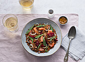 Closeup of a salmon and lentil salad seen from above on a table with a pink tablecloth