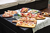 From above of assorted tasty appetizers served on table with tablecloth on terrace