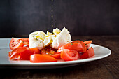 Reife Tomatenscheiben und Mozzarellakäse auf weißem Teller serviert