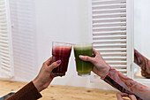 Unkenntlich gemachte multiethnische Freundinnen sitzen an der Theke und trinken einen erfrischenden Smoothie, während sie in einer Bar chillen
