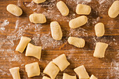 From above top view of uncooked gnocchi placed in rows on lumber table during lunch preparation at home