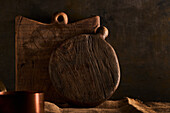 Handmade wooden chopping board of brown color placed on rustic table near pot in kitchen