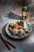 From above of baklava and biscuits with Moroccan peppermint tea near knife and fork placed on table decorated with mint leaves