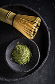 From above of dried tea leaves in heap on plate with chasen for tea ceremony