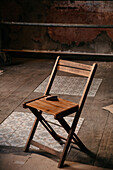 Hoher Winkel eines Stuhls auf staubigem Parkett und Fliesenboden in einem unordentlichen Raum während Reparaturarbeiten