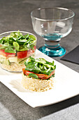 High angle of tasty salad of rice and vegetables in round shape and served in glass placed on white plate on gray table