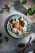 From above of baklava and biscuits with Moroccan peppermint tea near knife and fork placed on table decorated with mint leaves