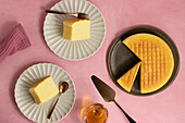 Top view of delicious cotton cheesecake served on plates near glass and spatula on pink background