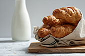 Delicious croissants and bottle of milk placed on table for breakfast in kitchen