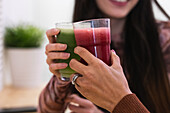 Unkenntlich gemachte multiethnische Freundinnen sitzen an der Theke und trinken einen erfrischenden Smoothie, während sie in einer Bar chillen