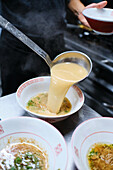 Stock photo of unrecognized chef in japanese restaurant serving noddles soup.