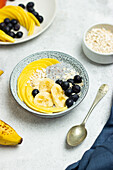 Hoher Blickwinkel auf appetitliches gesundes Müsli mit Chiasamen, Bananenscheiben, Mango und Blaubeeren zum Frühstück