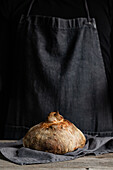 Unrecognizable crop chef in apron standing with piece of freshly baked bread