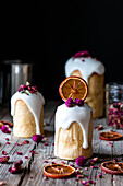 Several delicious homemade kulichs poured with sweet glaze and decorated with pieces of dry orange and flowers on wooden table