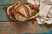 Top view of homemade sourdough bread with salmon served on wooden cutting board with cherry tomatoes on shabby table