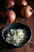 Top view of rustic bowl with pieces of cut onion placed on lumber table in kitchen