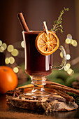 Gluhwein or christmas punch mulled wine server on a glass mug with dried orange slices
