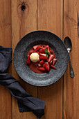 Top view of tasty flambeed strawberry halves with vanilla ice cream in plate on wooden table