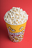 Top view bowl full of popcorn on a red background