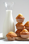 Yummy homemade freshly baked sweet muffins in paper cups arranged on table with glass jar of fresh milk