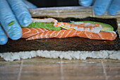 Stock photo of unrecognized chef in japanese restaurant preparing sushi plate.