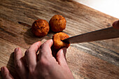 Von oben der Ernte anonymen Koch Schneiden knusprig frittierten Käse Ball auf hölzernen Schneidebrett
