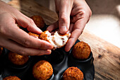 From above of crop anonymous chef demonstrating filling of cheese ball in crispy crust in kitchen