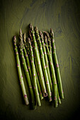 Top view of heap of raw asparagus stalks with uneven surface and wavy edges