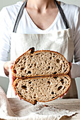Crop faceless woman hands holding freshly baked sourdough rye bread Crumb white cutting in half