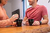 Crop Paar mit Tassen Kaffee stehen an der Theke in Licht stilvolle Küche mit zu Hause