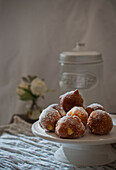 Homemade custard cream fritters covered with sugar on rustic wooden table with table cloth and leafs decoration