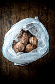 From above of ripe tropical eddo vegetables in plastic bag placed on wooden table