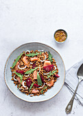 Closeup of a salmon and lentil salad seen from above on a table with a pink tablecloth