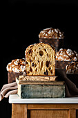 Delicious halve and whole of homemade panettones placed on aged books on wooden table against black background