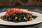 Schwarze Spaghetti mit Tintenfischtinte, garniert mit Garnelen und Sprossen, serviert auf einem Teller während des Mittagessens im Restaurant