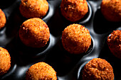 High angle of tasty roasted cheese balls in baking dish on concrete table in the kitchen