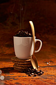 Ceramic mug of hot coffee bean spoon place on surface near pile of fresh baked oatmeal cookies