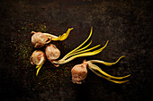 Top view layout of old onion bulbs with green sprouts placed together on black surface