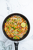 From above tasty stir fry rice noodles with vegetables served in frying pan