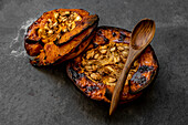 From above of tasty appetizing healthy baked pumpkin halves with seeds on gray table