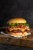 Detail of a delicious burger with cheese and bacon on the wooden table