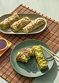 Cabbage spring rolls served on bamboo place mat near chopsticks