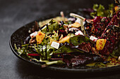 Plate with tasty vegetarian Indonesian salad with fresh mango and cashew cheese slices near soybeans and condiments covered with basil vinaigrette