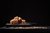 Gourmet quince jelly paste in ceramic plate sprinkled with sesame seeds on black background