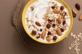 From above yoghurt served with oats and dried nuts on brown background