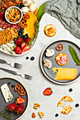 Top view of tasty charcuterie plate with assorted cheese and mushrooms served with ripe strawberries on table in light kitchen
