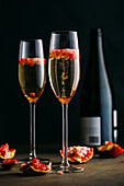 Champagne cocktail with pomegranate placed on rustic surface against dark background