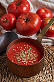 Top view of pan with delicious homemade tomato sauce and sprinkle of oregano placed on woven mat on wooden table in kitchen